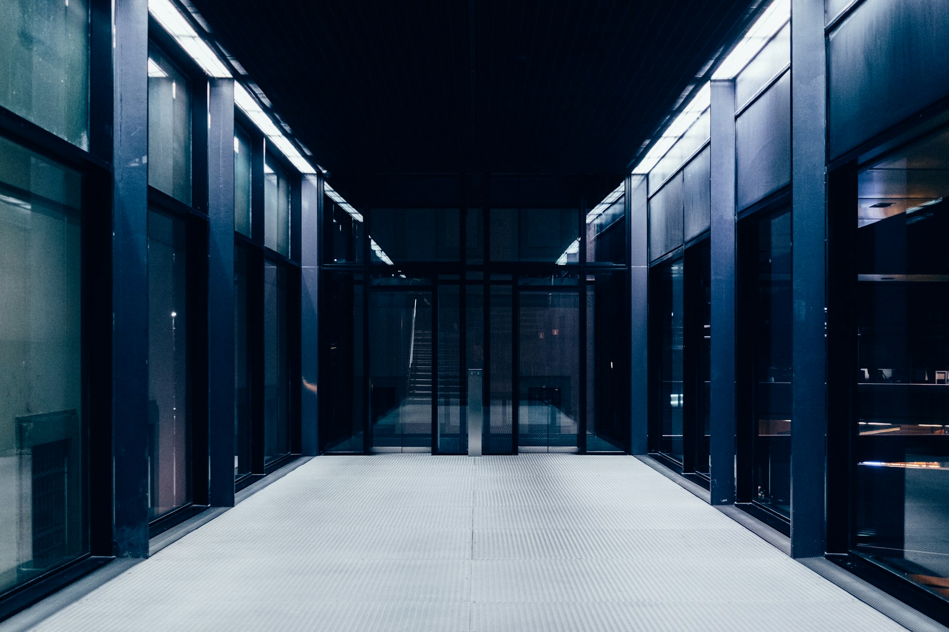 Long corridor lined with closed glass doors leading to interior rooms beyond.